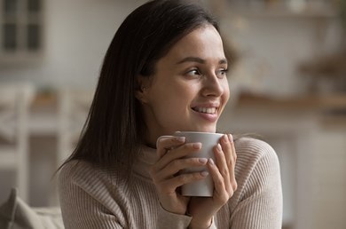 Eine junge Frau entspannt auf der Couch mit einer Tasse Tee