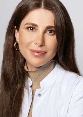 Portrait von Dr. Emi Arpa Dermatologin in weißem Kittel vor neutralem Hintergrund