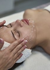Junge Frau bekommt eine Gesichtsbehandlung mit einer Creme im Gesicht.