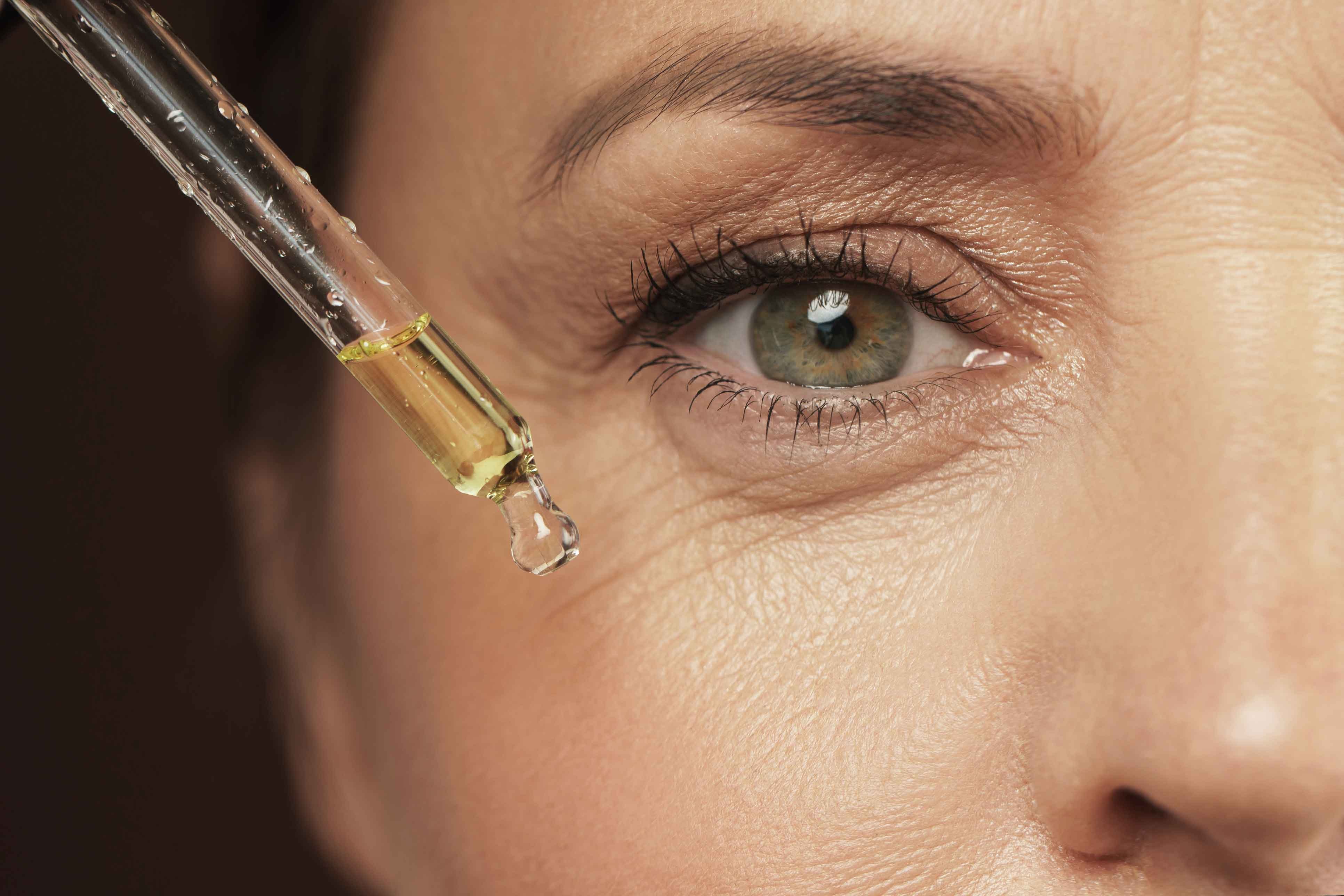 Nahaufnahme eines weiblichen Auges, daneben eine Pipette mit Gesichtsserum