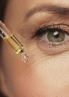 Nahaufnahme eines weiblichen Auges, daneben eine Pipette mit Gesichtsserum