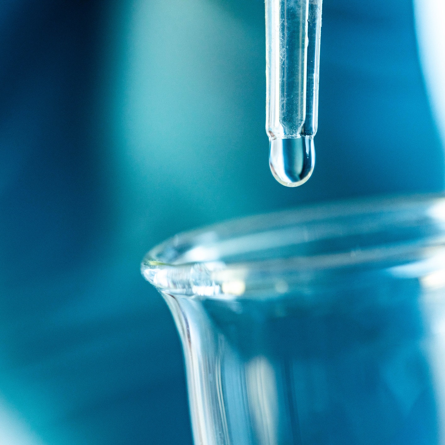 Tropfen aus einer Pipette über einem Glasbecher im Labor