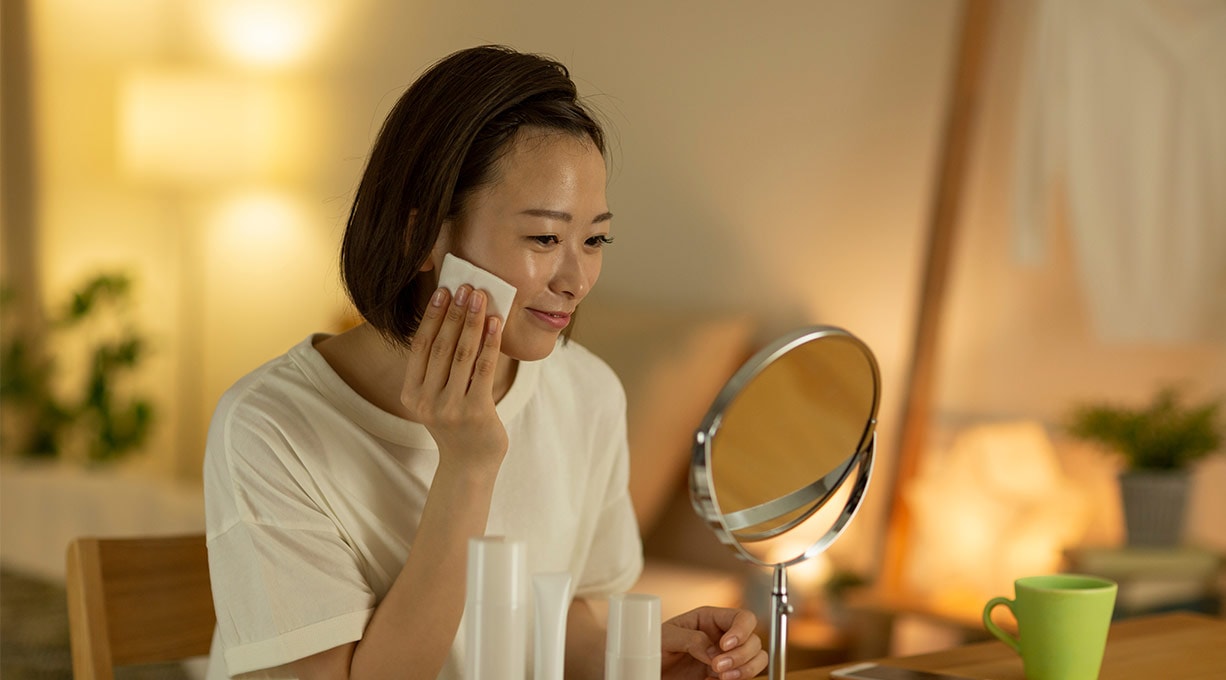 Eine junge Frau pflegt ihr Gesicht vor einem Kosmetikspiegel