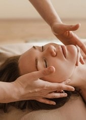 Eine entspannt aussehende Frau bekommt eine Gesichtsmassage.