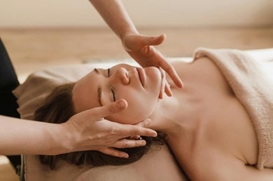 Eine entspannt aussehende Frau bekommt eine Gesichtsmassage.