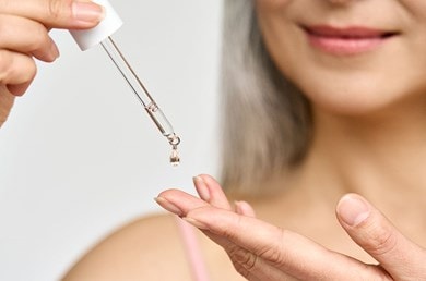 Frau trägt Anti-Aging-Serum mit Kollagen und Hyaluron mit einer Pipette auf