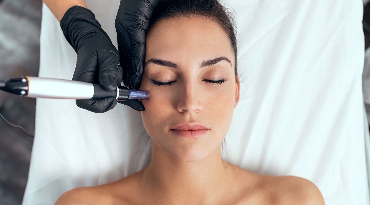 Kosmetische Behandlung im Gesicht mit Gerät, Frau liegt entspannt mit geschlossenen Augen