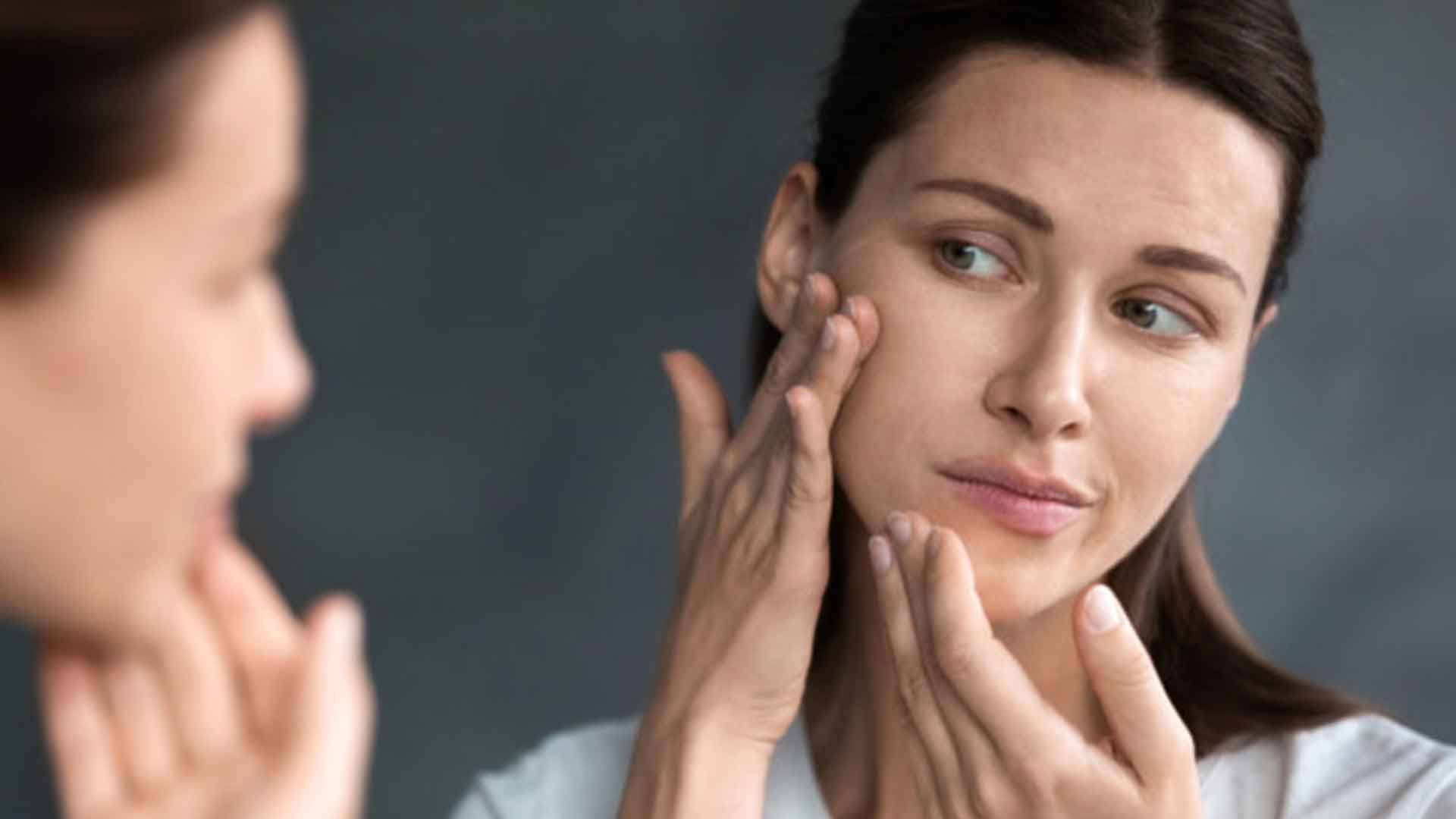 Frau betrachtet ihre Nasolabialfalte im Gesicht