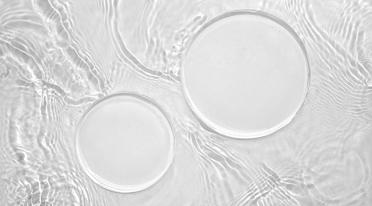 Zwei klare Tropfen Serum auf transparenter Textur als Produktvisualisierung