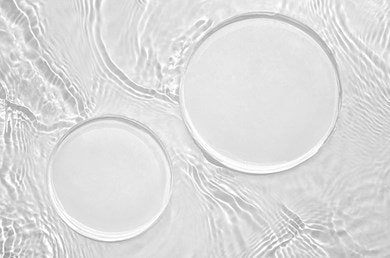 Zwei klare Tropfen Serum auf transparenter Textur als Produktvisualisierung
