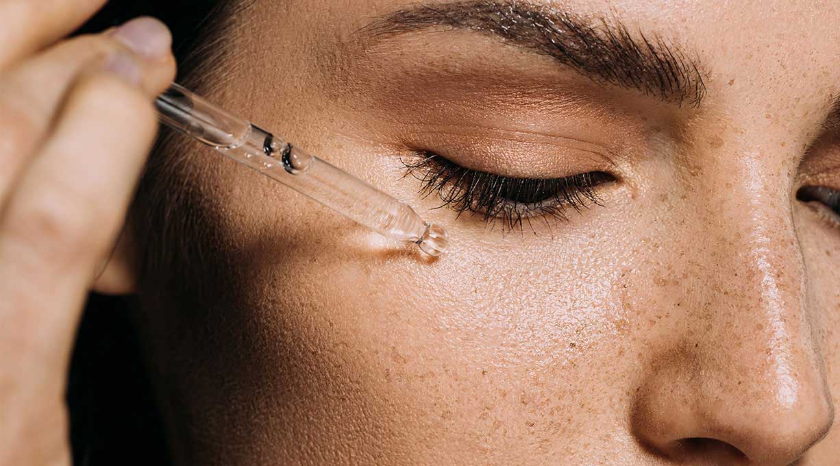 Nahaufnahme eines Gesichts mit Pipette bei der Anwendung eines Serums gegen Pigmentflecken