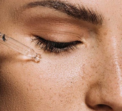 Nahaufnahme eines Gesichts mit Pipette bei der Anwendung eines Serums gegen Pigmentflecken