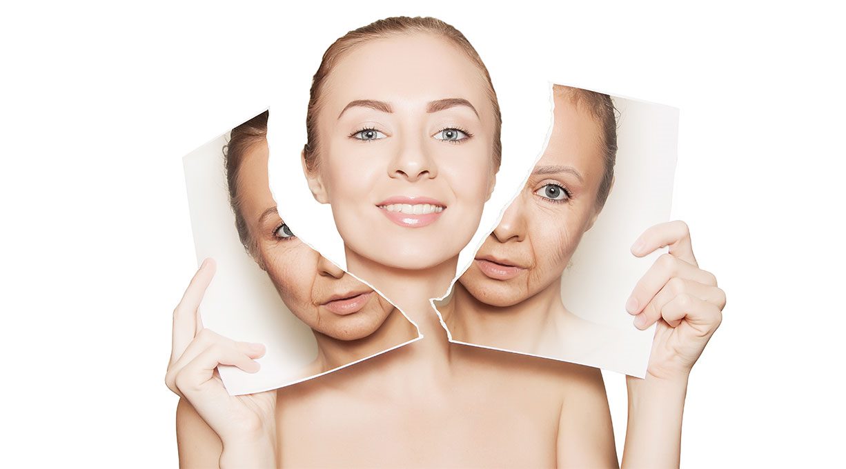 Lächelnde Frau hält zerrissenes Foto mit jüngerem und älterem Hautbild in den Händen