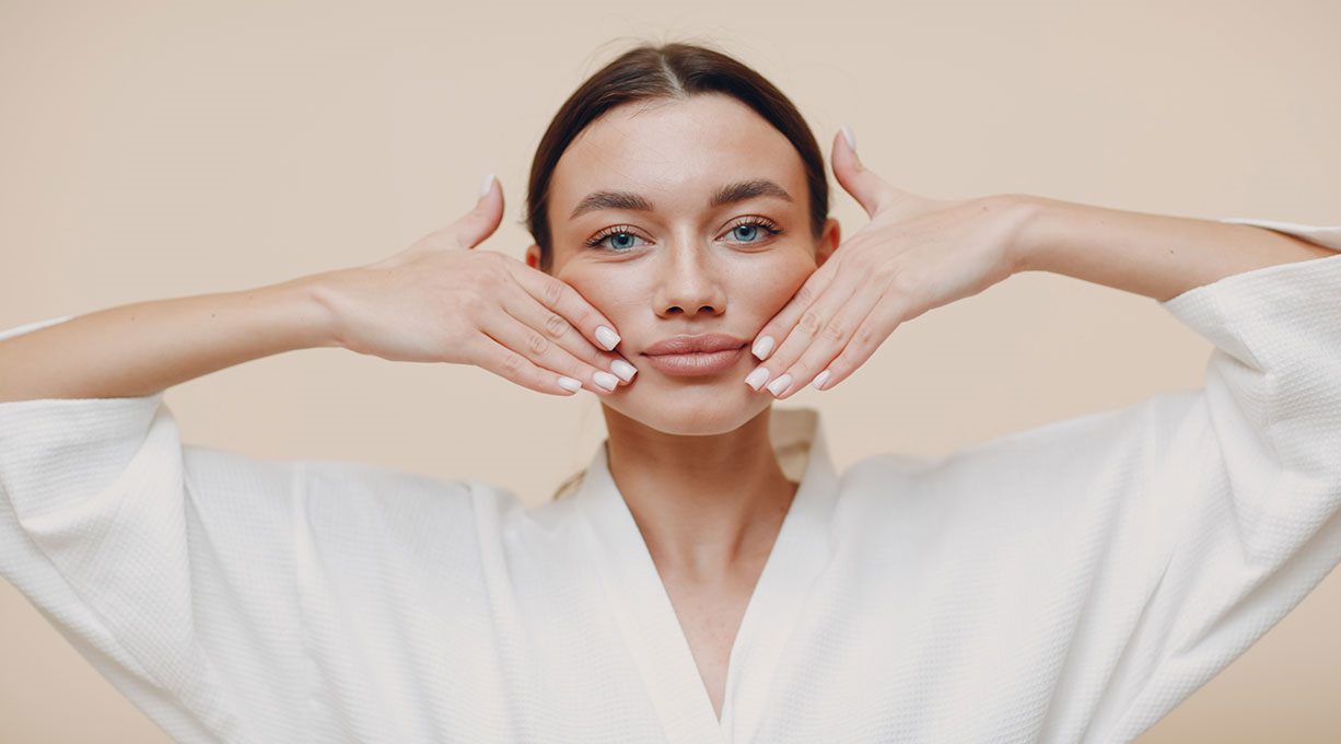 Frau führt Gesichtsyoga-Übung mit Händen zur Straffung der Gesichtshaut aus