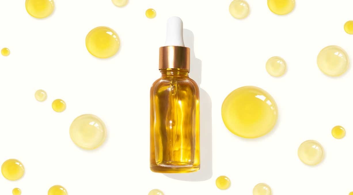 Anti-Aging-Serum gegen Stirnfalten in Glasfläschchen mit Pipette und goldgelben Tropfen.