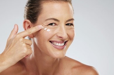 Lächelnde Frau verwendet feuchtigkeitsspendendes Anti-Aging-Serum.