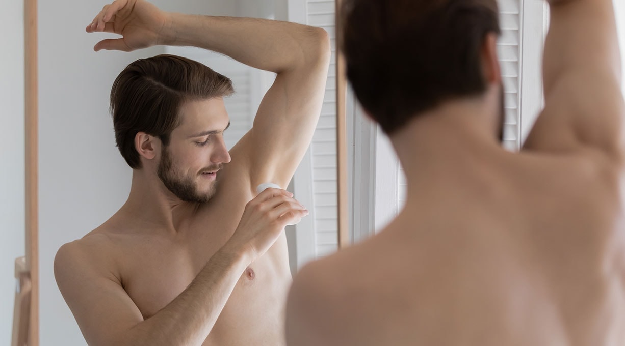 Mann trägt Deo Roll-on unter der Achsel auf, um starkes Schwitzen und Körpergeruch zu reduzieren.