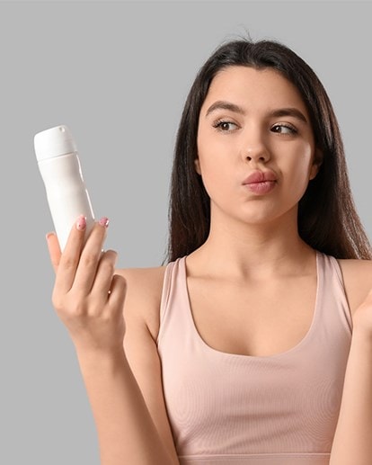 Frau vergleicht Spray und Deo-Stick, um das passende Produkt gegen Schwitzen zu wählen.