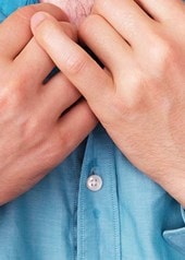 Mann mit schweißnassem Hemd im Brustbereich hält den Kragen mit beiden Händen fest