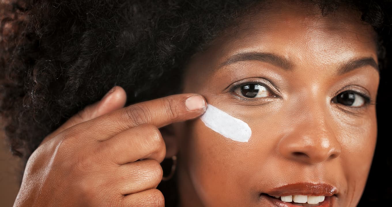 Frau trägt Creme mit Hyaluron unter dem Auge auf