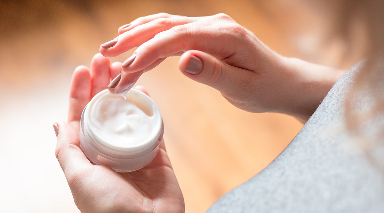 Weibliche Hände entnehmen Feuchtigkeitscreme zur Pflege dehydrierter Gesichtshaut