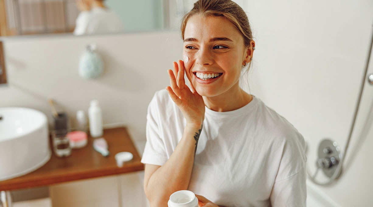 Frau trägt Gesichtscreme auf, effektive Pflege bei dehydrierter Haut
