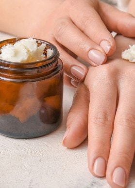 Nahaufnahme von Hände tragen pflegende Sheabutter auf, natürliche Feuchtigkeitspflege für trockene Haut