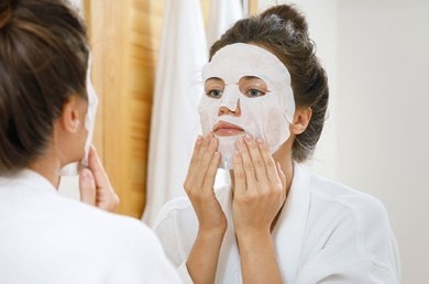 Frau trägt feuchtigkeitsspendende Tuchmaske auf, intensive Pflege für strahlend frische Haut