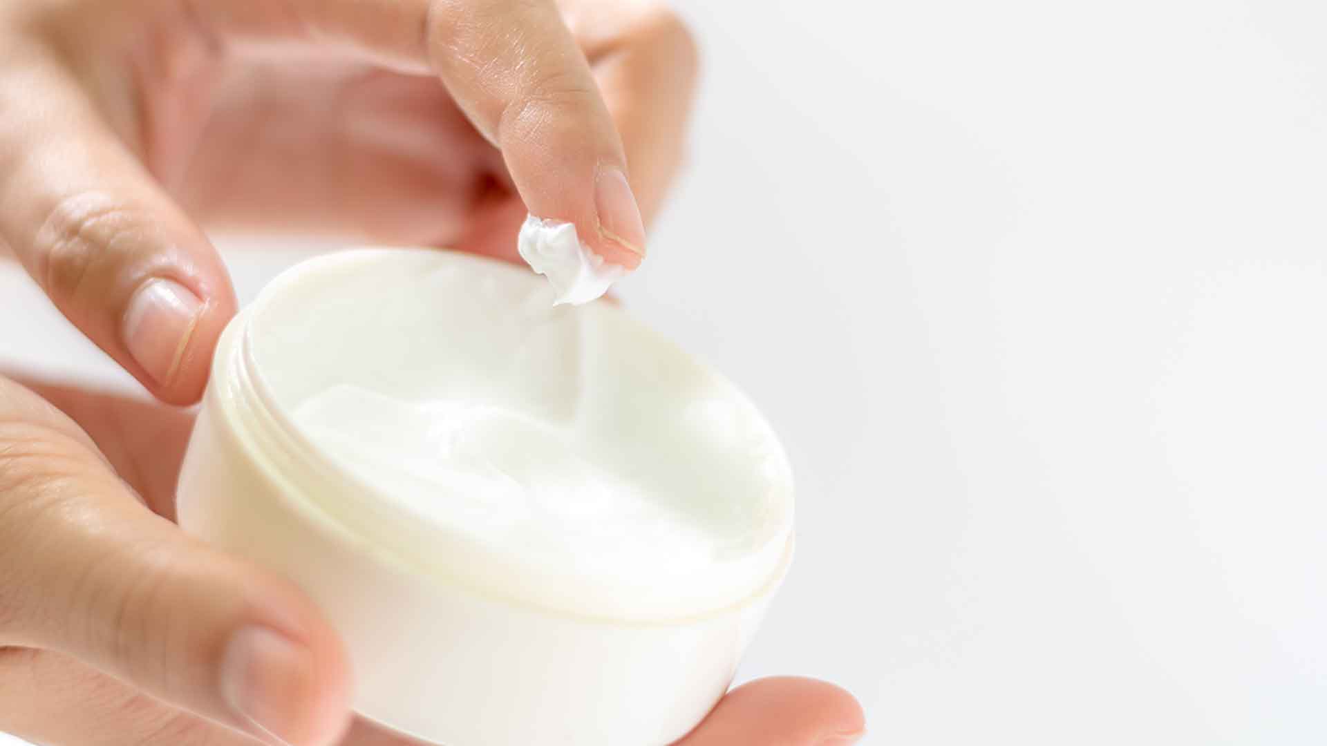 Eine Hand entnimmt zarte Creme aus Tiegel, symbolisiert passende Feuchtigkeitspflege für jeden Hauttyp