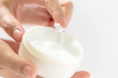 Eine Hand entnimmt zarte Creme aus Tiegel, symbolisiert passende Feuchtigkeitspflege für jeden Hauttyp