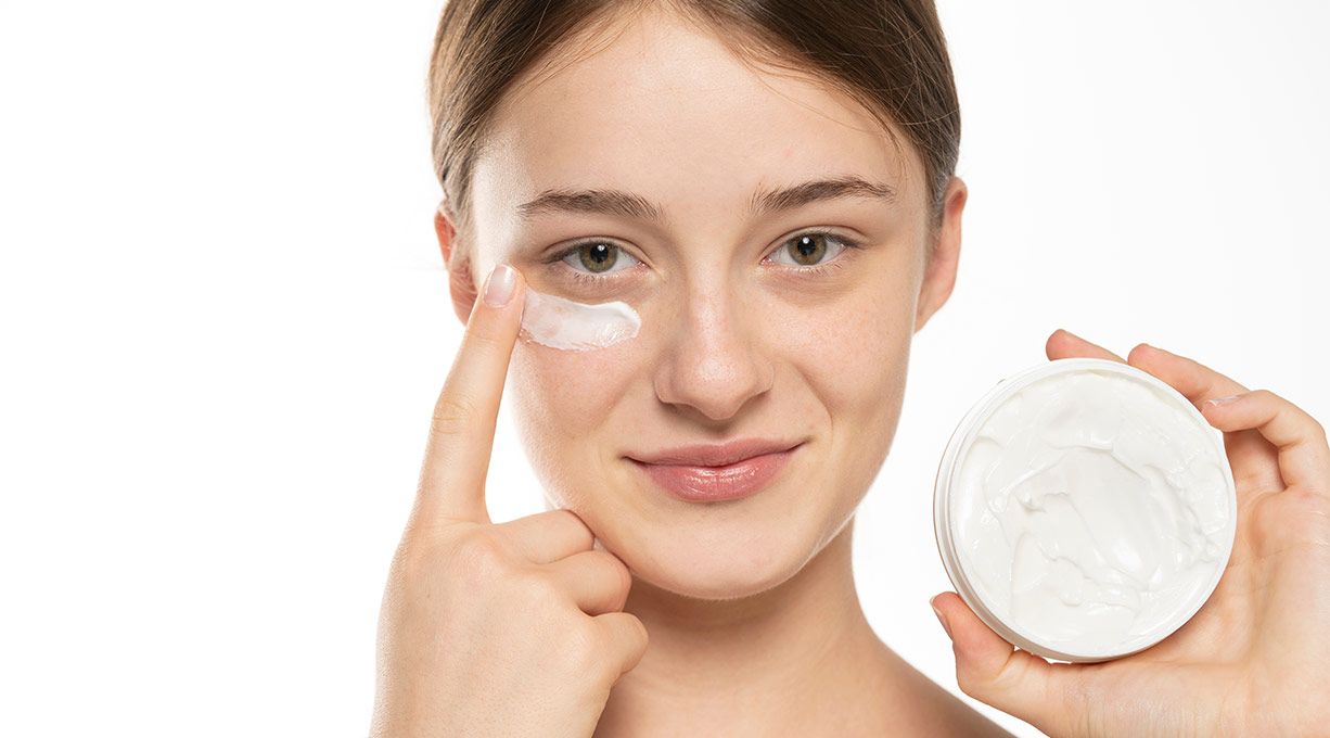 Junge Frau trägt Creme unter den Augen auf, erfrischender Feuchtigkeitskick für müde Haut