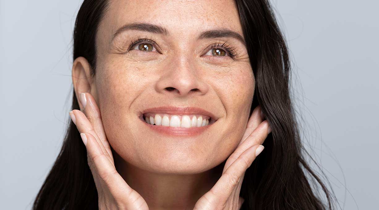 Lächelnde Frau mit gesunder Haut, zeigt Wirkung eines nährenden Gesichtsserums