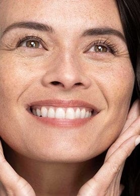 Lächelnde Frau mit gesunder Haut, zeigt Wirkung eines nährenden Gesichtsserums