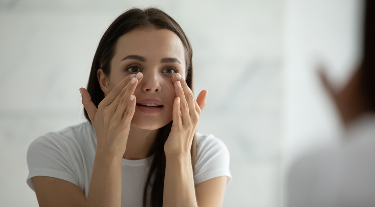 Braunhaarige frau behandelt ihre augenringe