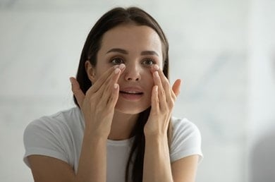 Braunhaarige frau behandelt ihre augenringe