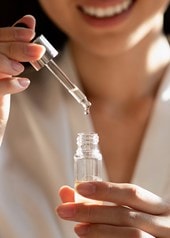 Frau hält die Pipette eines geöffneten Serums in der Hand