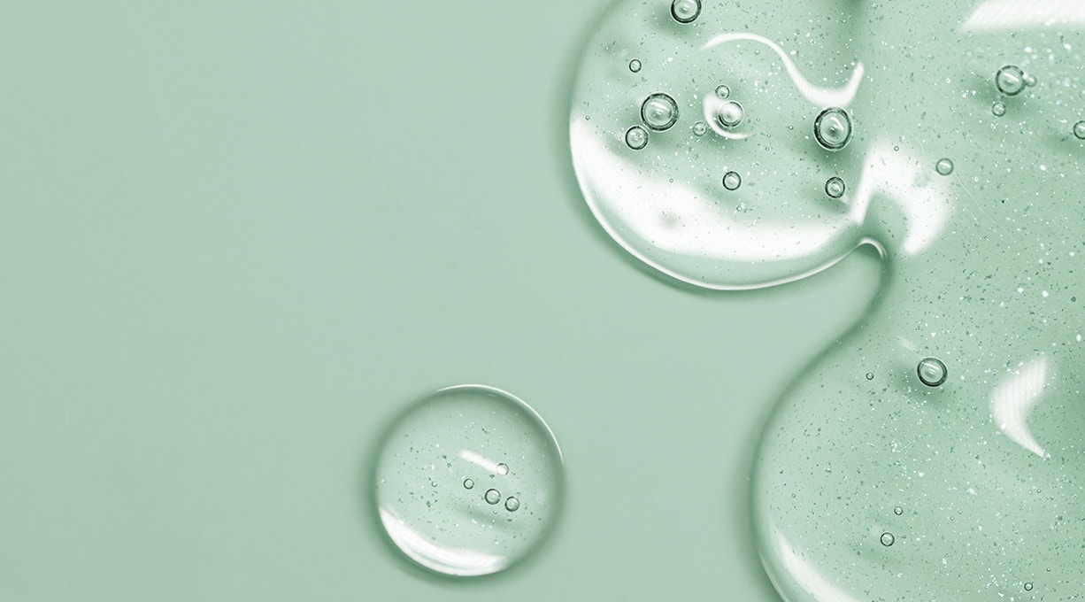 Gelartige Textur eines Gesichtsserums auf mintgrünem Untergrund