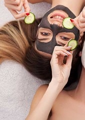 2 junge Frauen mit Gesichtsmasken und Gurkenscheiben in der Hand