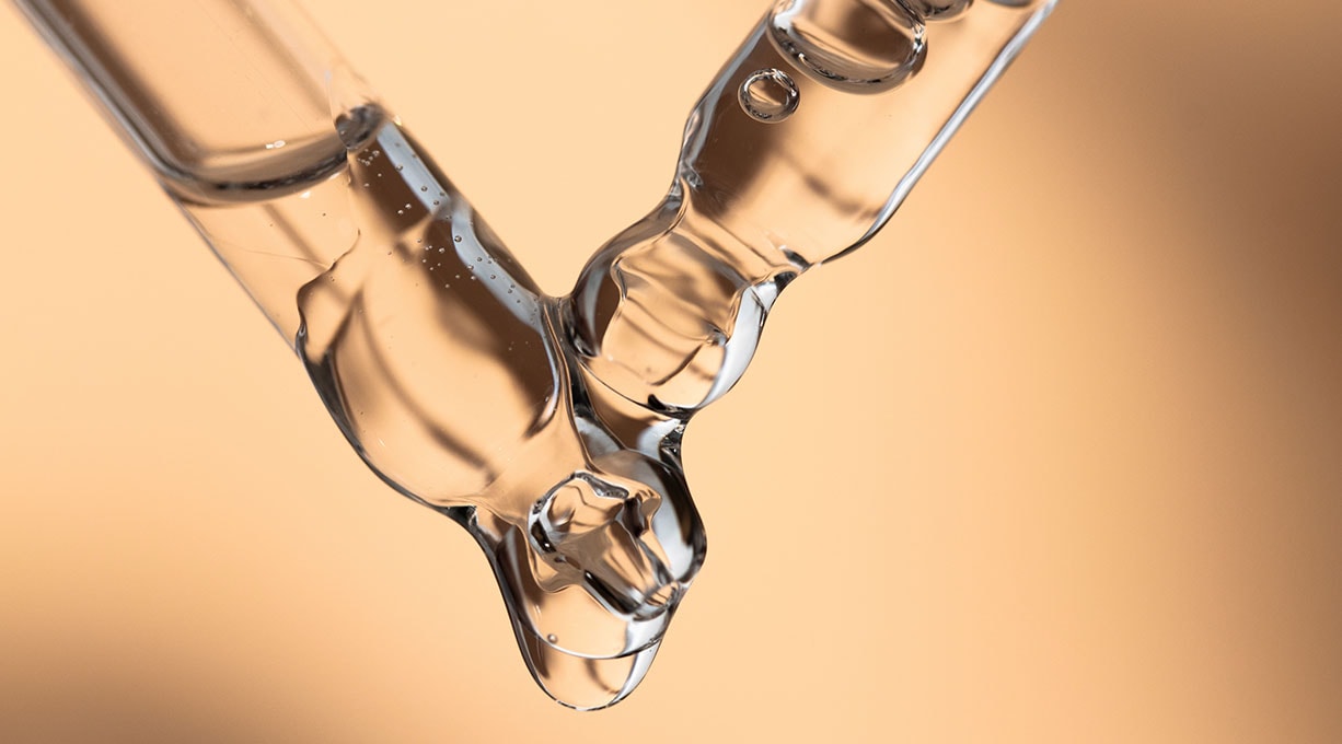 Zwei Pipetten mit Serum aneinander vor dunkelgelbem Hintergrund