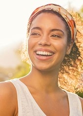 Junge Frau steht draußen in der Sonne und lacht