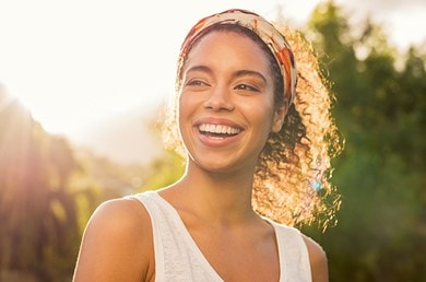 Junge Frau steht draußen in der Sonne und lacht