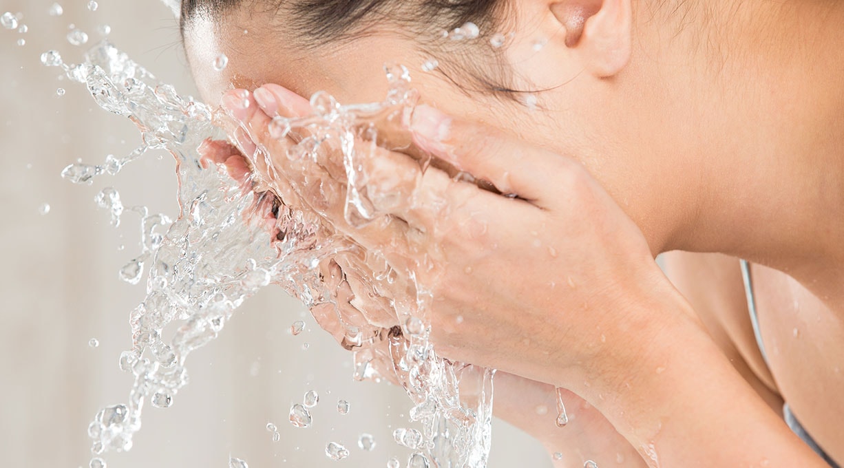 Frau bespritzt ihr Gesicht mit Wasser