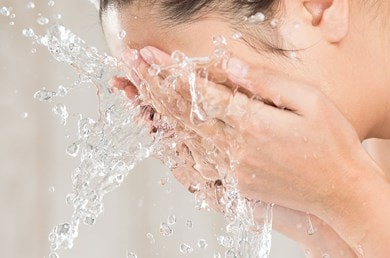 Frau bespritzt ihr Gesicht mit Wasser