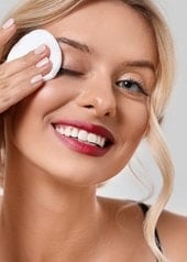 Blonde junge Frau schminkt sich mit einem Wattepad ab