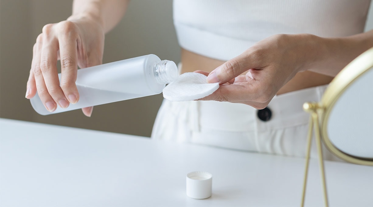 Person trägt Make-up-Entferner auf einem Wattepad auf