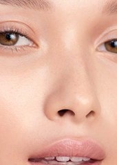 Frau mit braunen Augen hält ihre Hände an die Schläfen