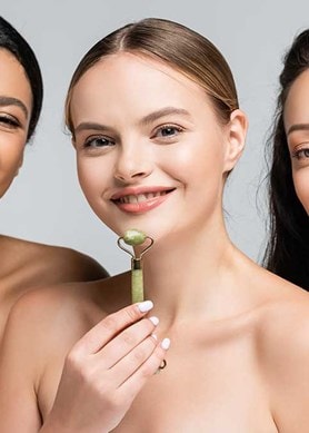 Drei junge Frauen halten verschiedene Gua Sha Tools für das Gesicht in der Hand