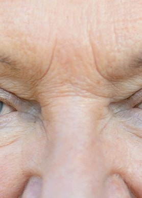 Nahaufnahme der Augenpartie einer älteren Frau mit sichtbaren Falten