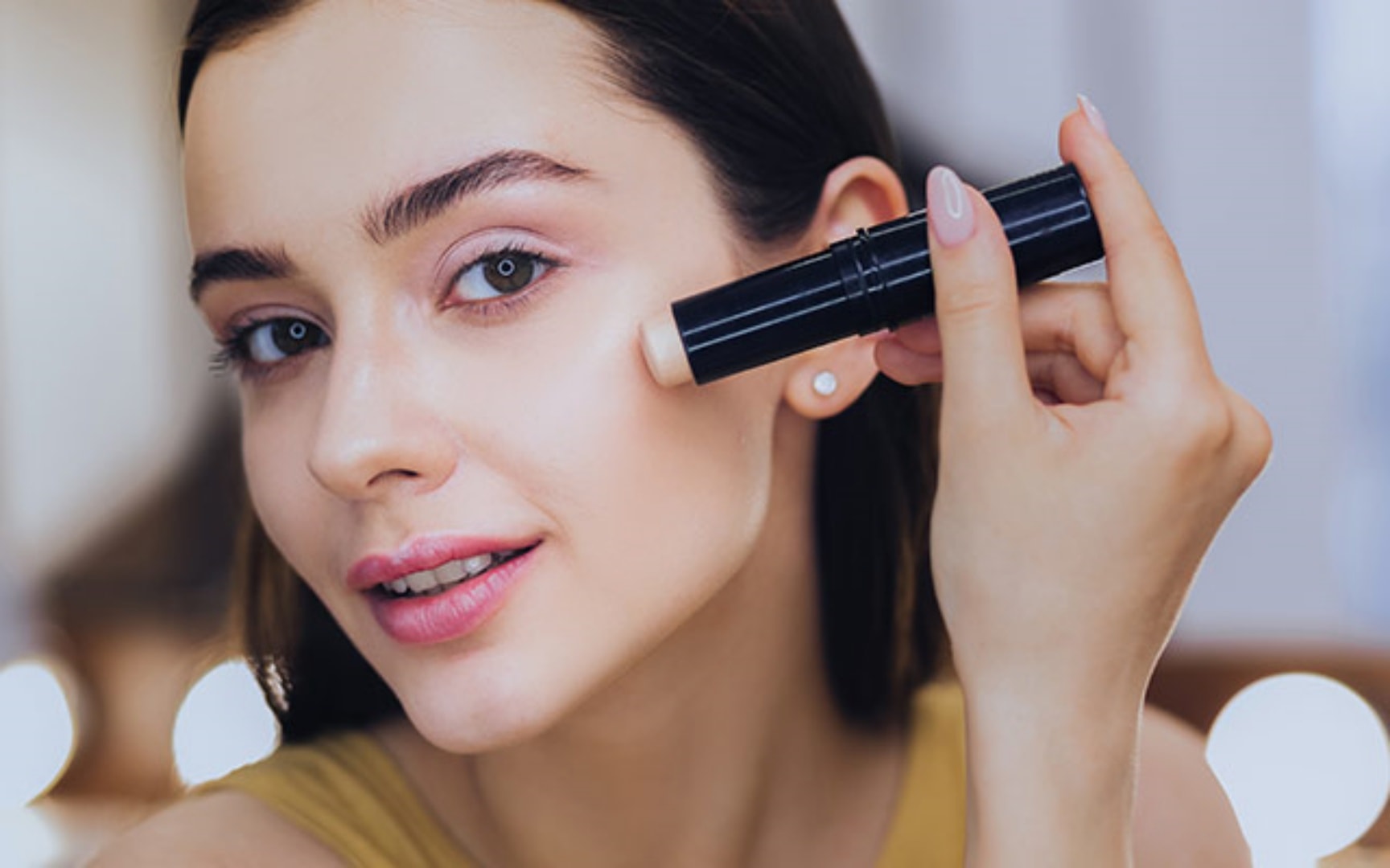 Eine Frau trägt Make-Up aus einem Stick auf ihr Gesicht auf