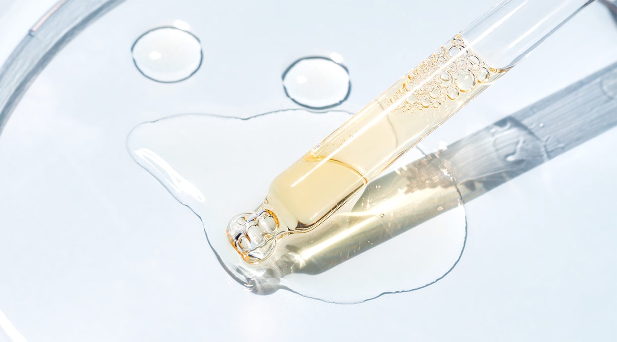 Pipette und ein paar Tropfen Retinol-Serum auf einer gläsernen Oberfläche